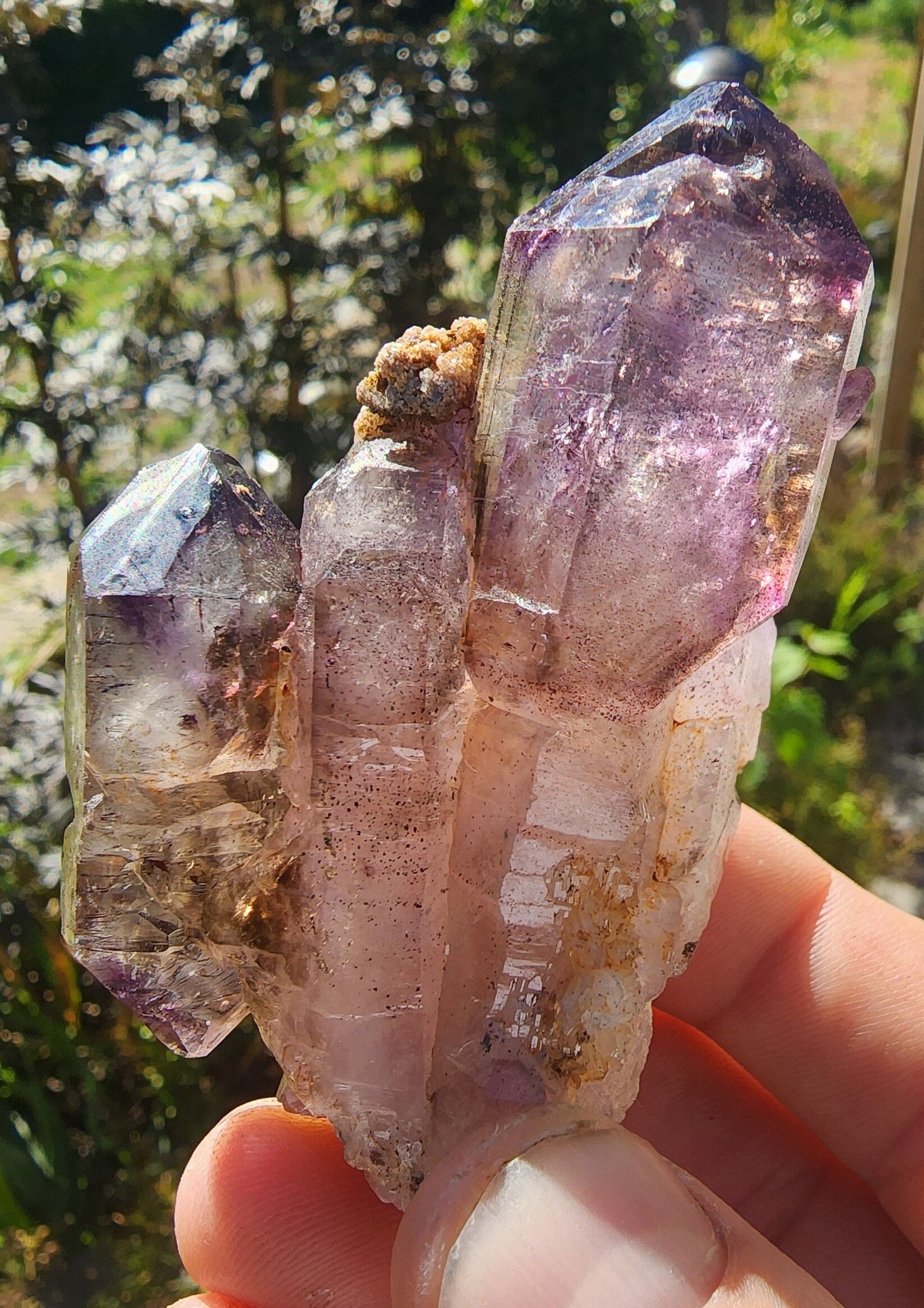 May include: Amethyst cluster featuring three main points, exhibiting a captivating blend of purple and clear quartz. The crystals showcase varying shades of purple, from deep violet to pale lilac, creating a stunning visual effect.  The cluster displays natural formations and textures, with some areas showing subtle brown inclusions. The overall appearance is one of natural beauty and elegance, highlighting the unique characteristics of amethyst crystals.